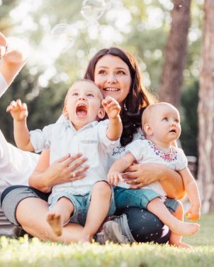 Joyful family enjoying a sunny day in the park while playing with bubbles.