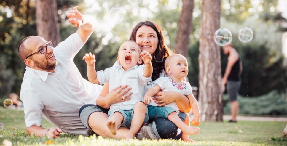 Joyful family enjoying a sunny day in the park while playing with bubbles.