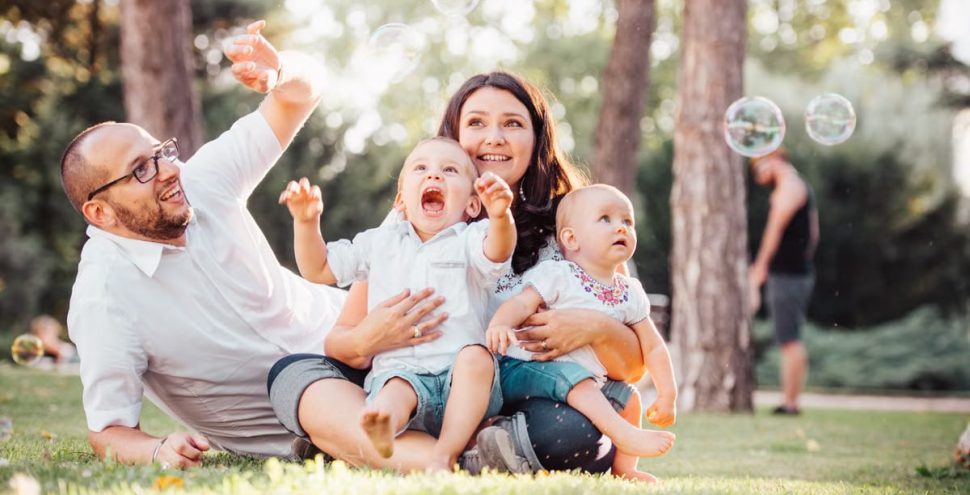 Joyful family enjoying a sunny day in the park while playing with bubbles.